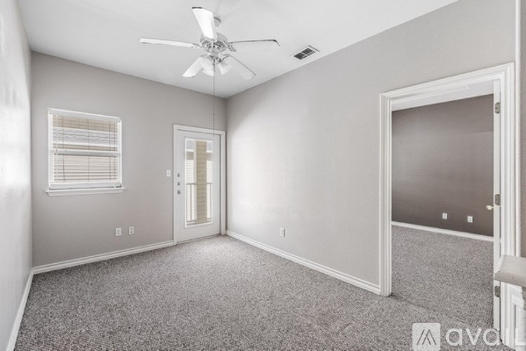 A room with a ceiling fan and carpeted floor.