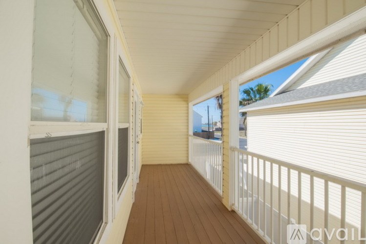 A balcony with a white railing and wooden floor.