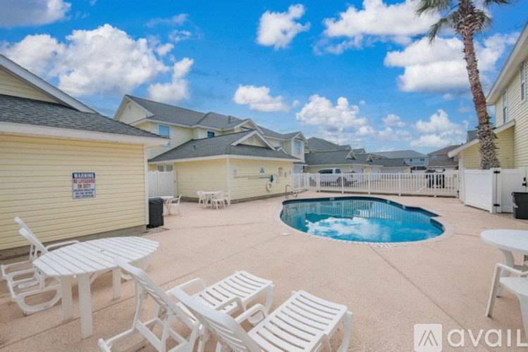 A pool surrounded by white chairs and a palm tree.