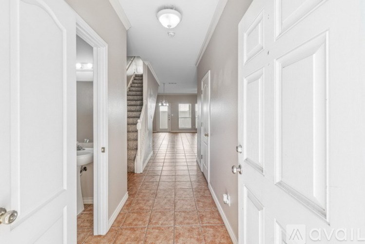 A hallway with a tiled floor and white walls.