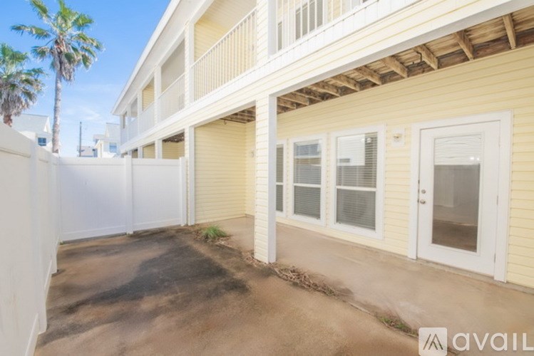 A yellow building with a white fence and a palm tree in the background.