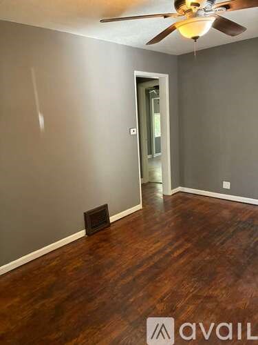 A room with a ceiling fan and wooden flooring.