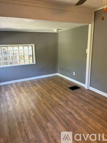 A room with wooden flooring and a window.