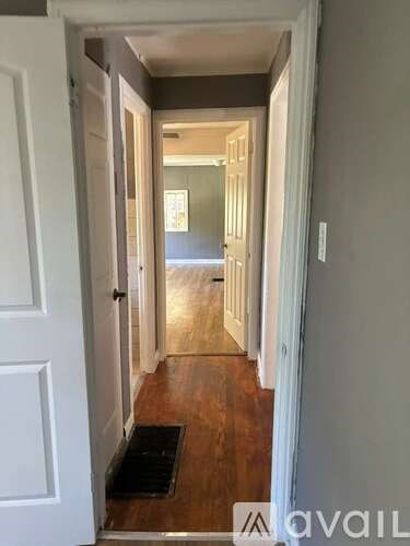 A hallway with a mat on the floor leading to a door.