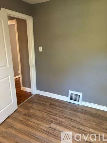 A room with a white door and a wooden floor.