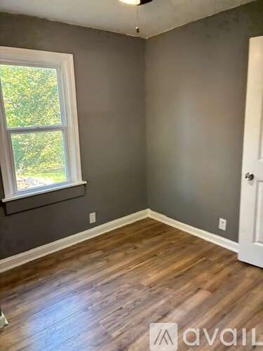 A room with a window and wooden flooring.