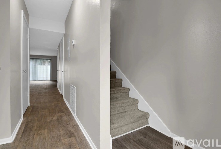 A hallway with a staircase and a door on the left.