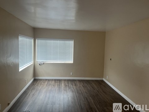 A room with wooden flooring and a window with blinds.