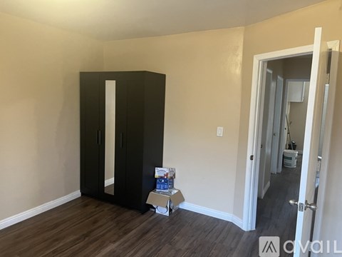 A black wardrobe stands in a room with a wooden floor.
