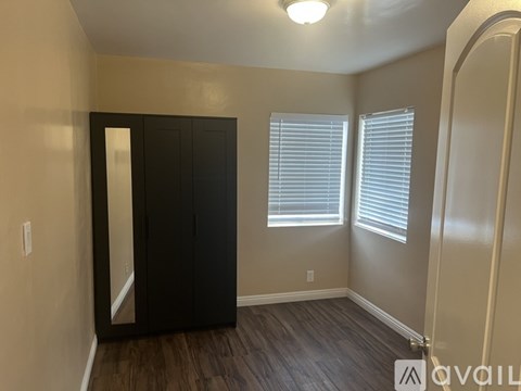 A bedroom with a black wardrobe and a window with blinds.