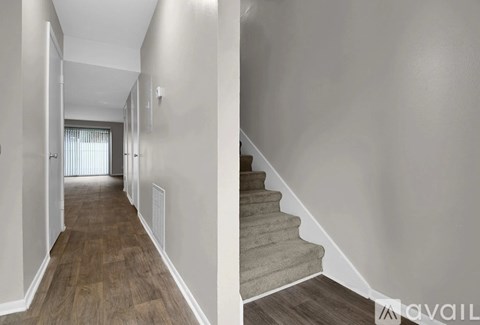 A hallway with a staircase and a door on the left.