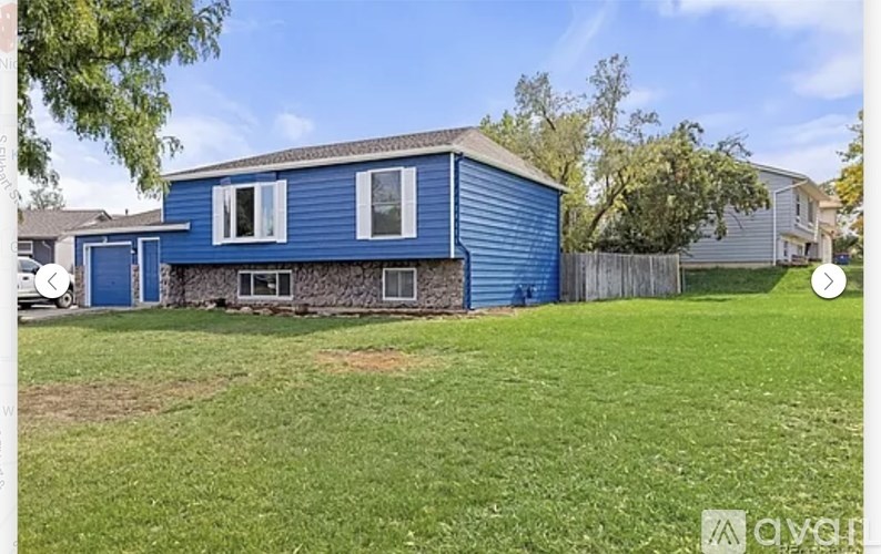 A blue house with a white fence and a green lawn.