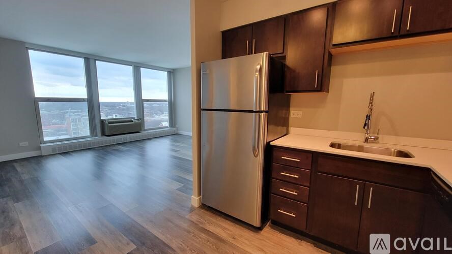 A kitchen with a refrigerator, sink, and wooden floors.