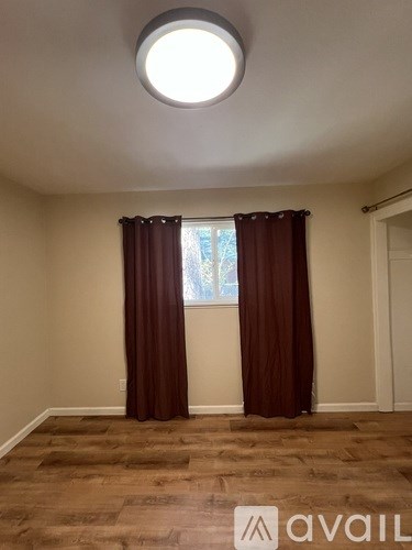 A room with a round window and brown curtains.
