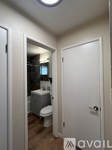 A bathroom with a toilet, sink and mirror.