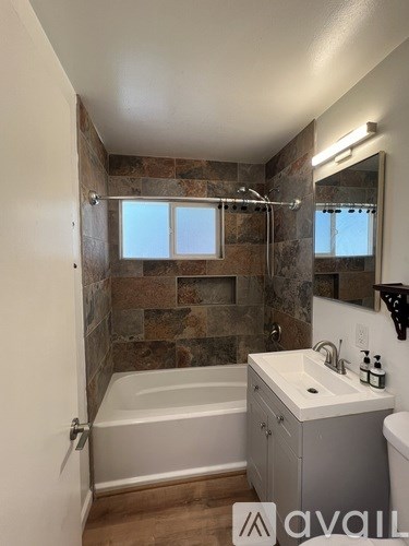 A bathroom with a tub, sink, and mirror.