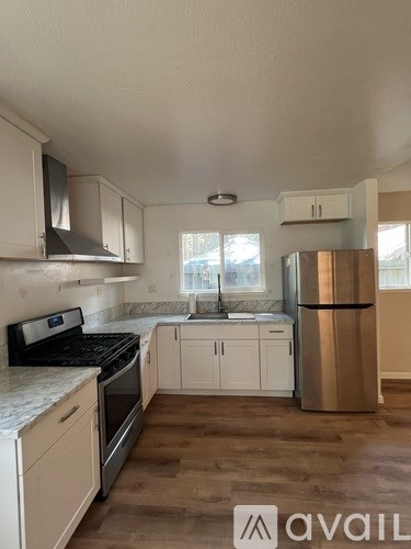 A kitchen with white cabinets and a stainless steel refrigerator.