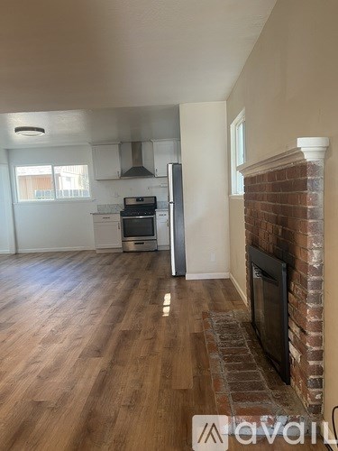 A living room with a fireplace and a kitchen area in the background.