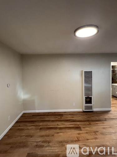 A room with a wood floor and a wall-mounted air conditioning unit.
