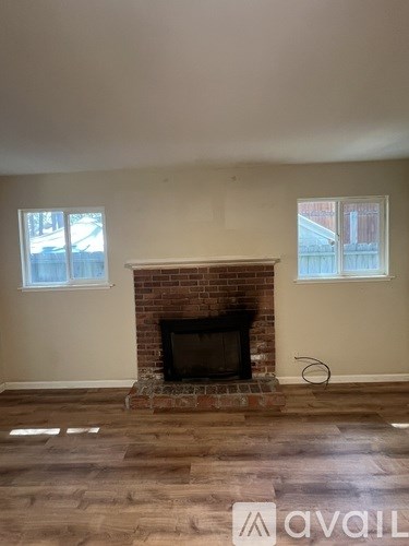A room with a brick fireplace and wooden floors.