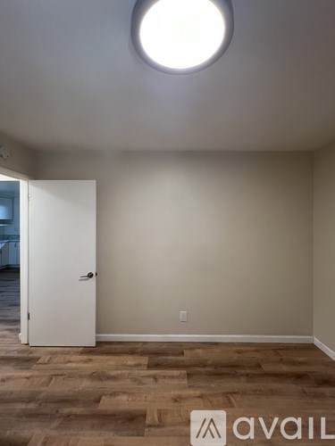 A room with a white door and wooden flooring.