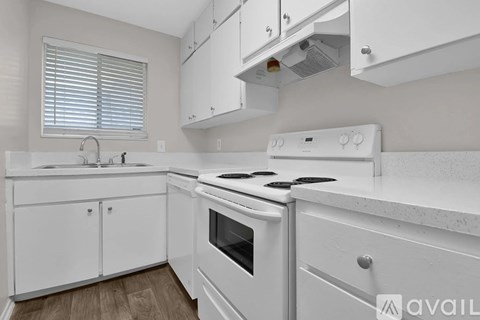 A white kitchen with a stove top oven and a sink.
