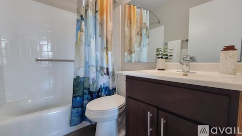 A bathroom with a white toilet, a bathtub with a shower curtain, and a counter with a mirror.