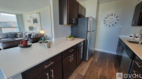 A kitchen with a white countertop and a fridge with a clock on the wall.