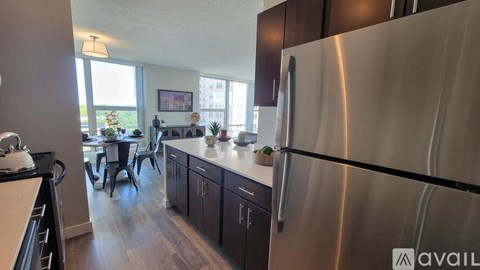 A kitchen with a stainless steel refrigerator and dark wood cabinets.