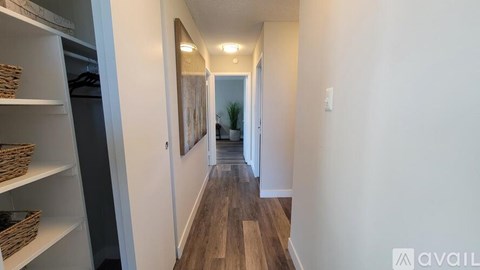A long hallway with a refrigerator on the left and a door on the right.
