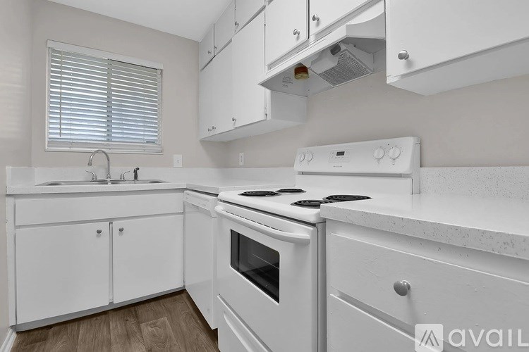 A white kitchen with a stove top oven and a sink.