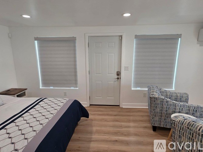 A bedroom with a bed, chair, and door.