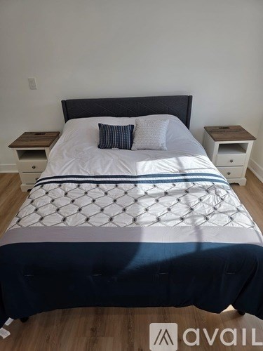 A bed with a white and blue comforter and a black headboard.
