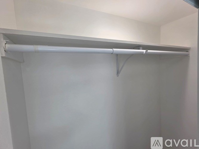 A white closet with a metal rod for hanging clothes.