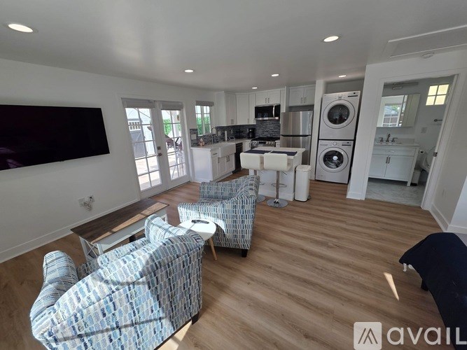 A modern living room with a television, two chairs, and a coffee table.