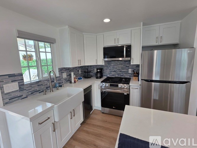 A kitchen with white cabinets and a stainless steel refrigerator.