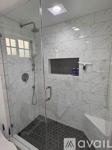 A bathroom with a marble wall and a walk-in shower.