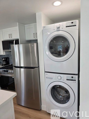 A stack of white front loading washing machines in a kitchen.
