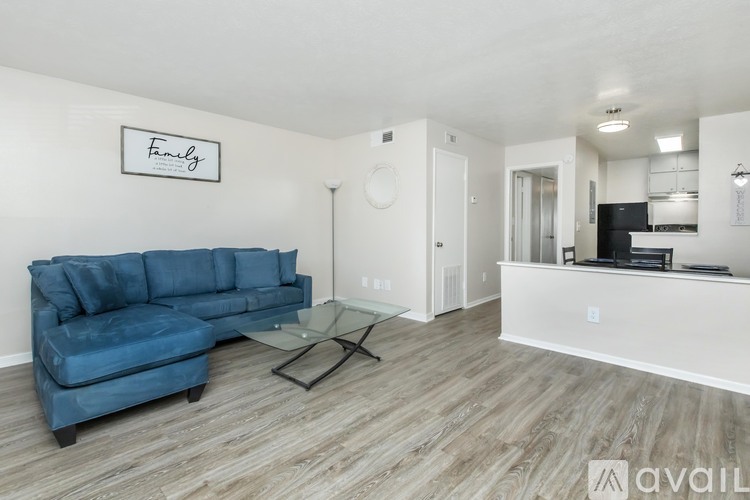 A living room with a blue couch and a glass coffee table.