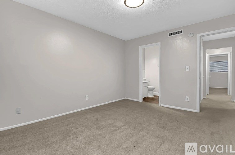 A spacious room with a carpeted floor and a staircase leading to another room.