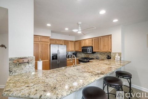A kitchen with granite countertops and wooden cabinets.