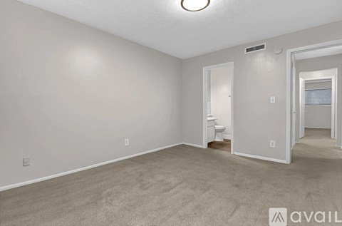 A spacious room with a carpeted floor and a staircase leading to another room.