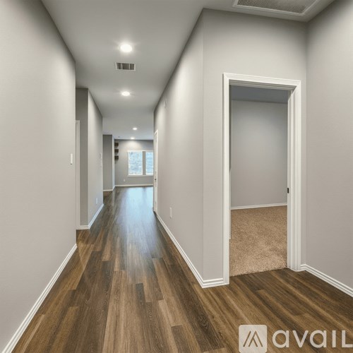A long hallway with wood floors and white walls.