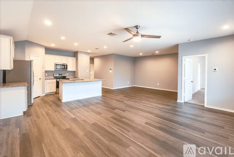 A spacious living room with a kitchen area in the background.