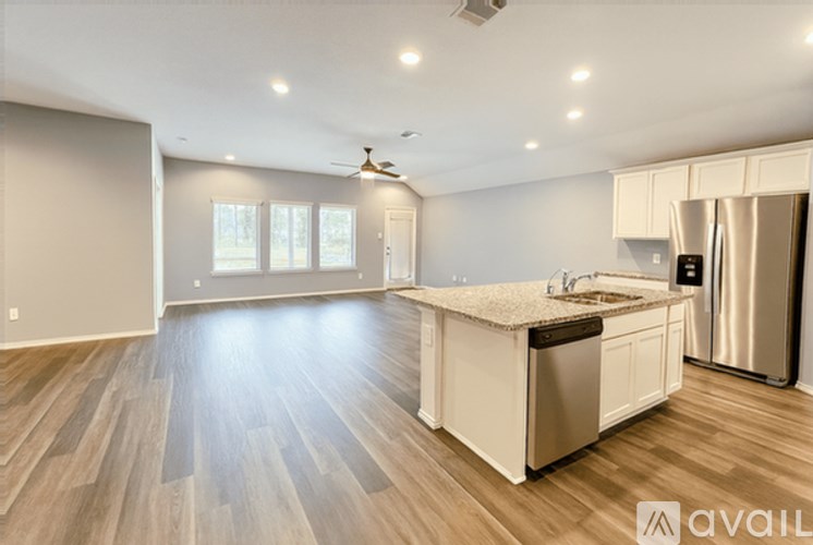 A spacious kitchen with wooden floors and stainless steel appliances.