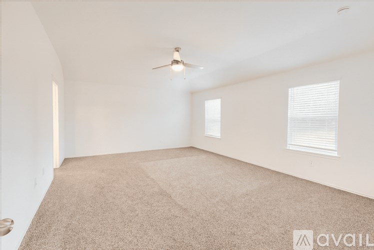 A spacious room with a carpeted floor and a ceiling fan.