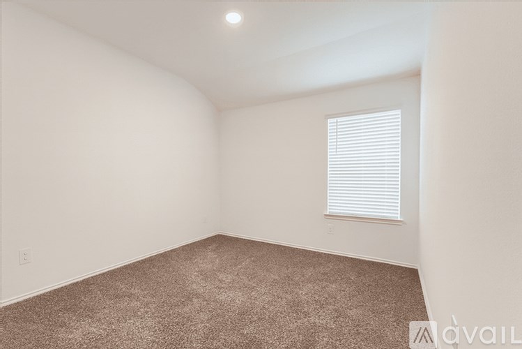 A room with a carpeted floor and a window with blinds.