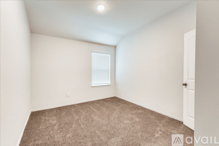A room with a carpeted floor and a window with blinds.