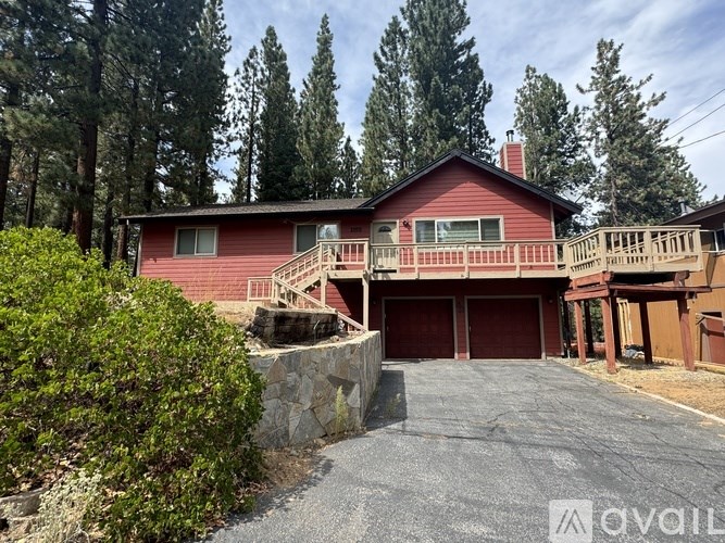 A red house with a stone wall and a gravel driveway.
