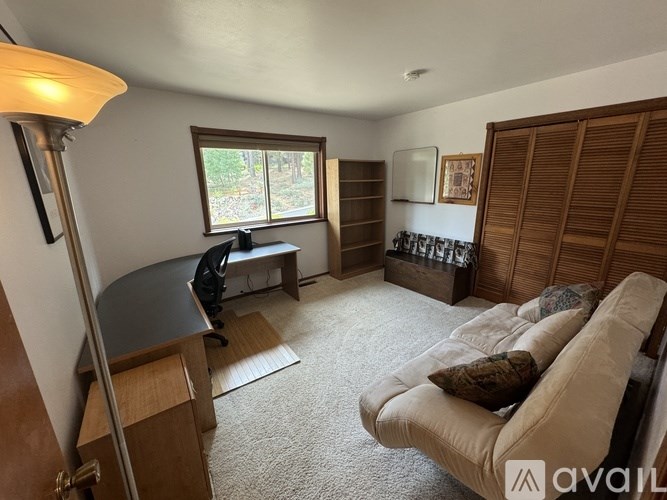 A living room with a couch, a chair, a lamp, and a window.